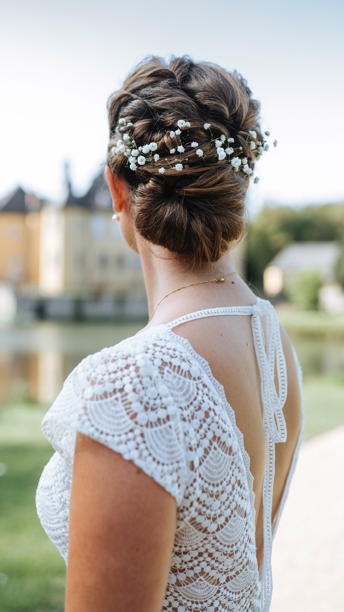 Braut mit Haarschmuck im Brautkleid blickt auf Schloss Dyck 