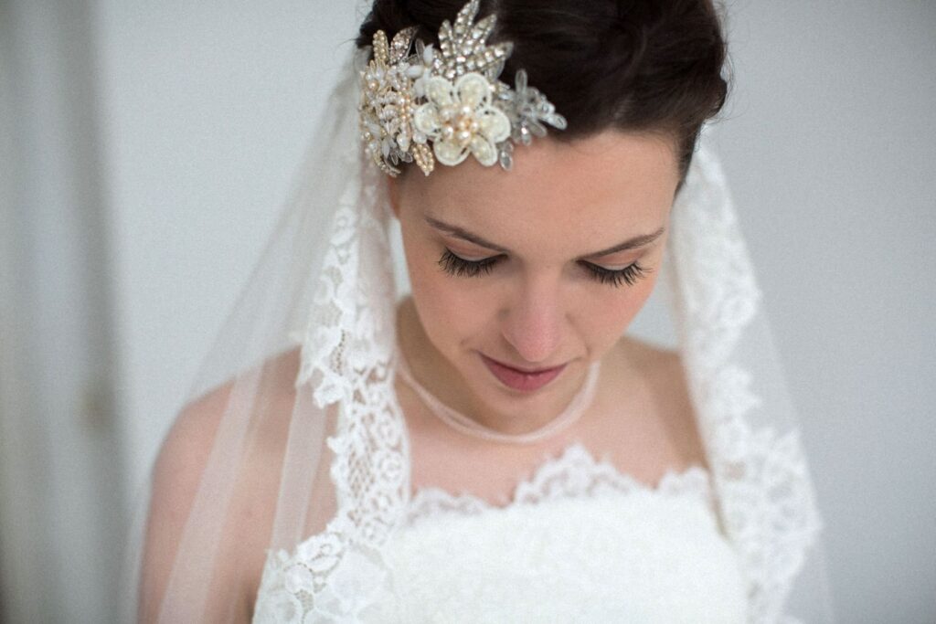 Braut mit dunklen Haaren, Spitzenschleier und Blüten-Haarschmuck mit Perlen