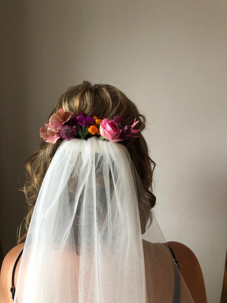 Halboffene Brautfrisur mit bunten Sommerblumen und Schleier von hinten