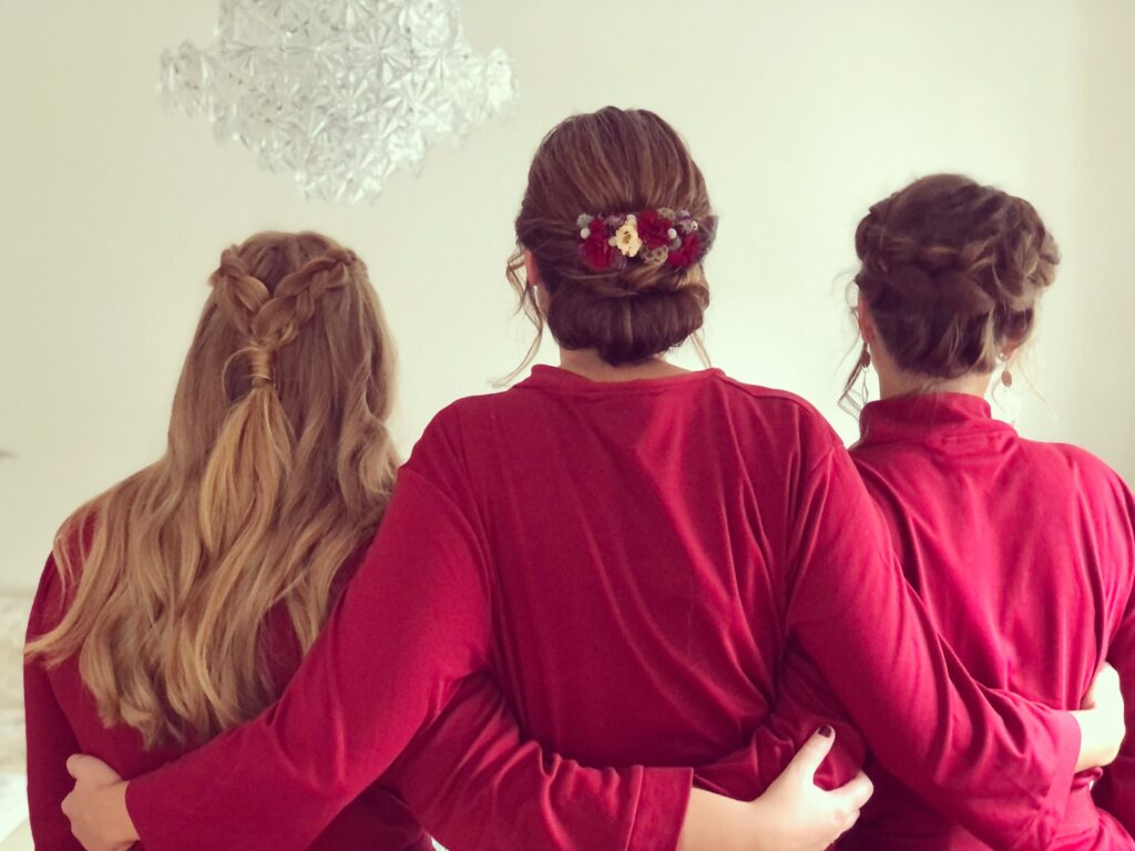 Drei Brautjungfern in Rot von hinten mit Flechtfrisur, Dutt mit Blüten und lockerer Hochsteckfrisur