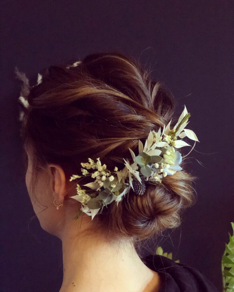 Tiefer, gedrehter Knoten bei dunklen Haaren mit Haarschmuck aus Eukalyptus und Trockenblumen