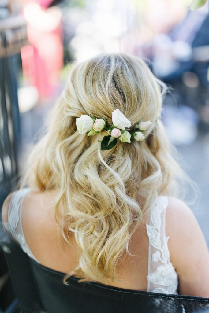 Blonde Brautfrisur mit weichen Wellen und frischen weißen Rosen am Hinterkopf